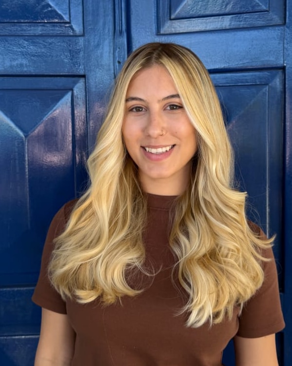 Ana Luísa Ferraz, psicóloga, sorrindo diante de uma porta azul